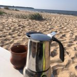 Espressokanne und Keramiktasse am Strand