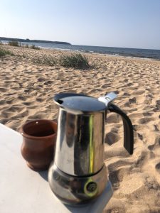 Espressokanne und Keramiktasse am Strand