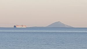 Container Schiff vor der Silhouette von Cres