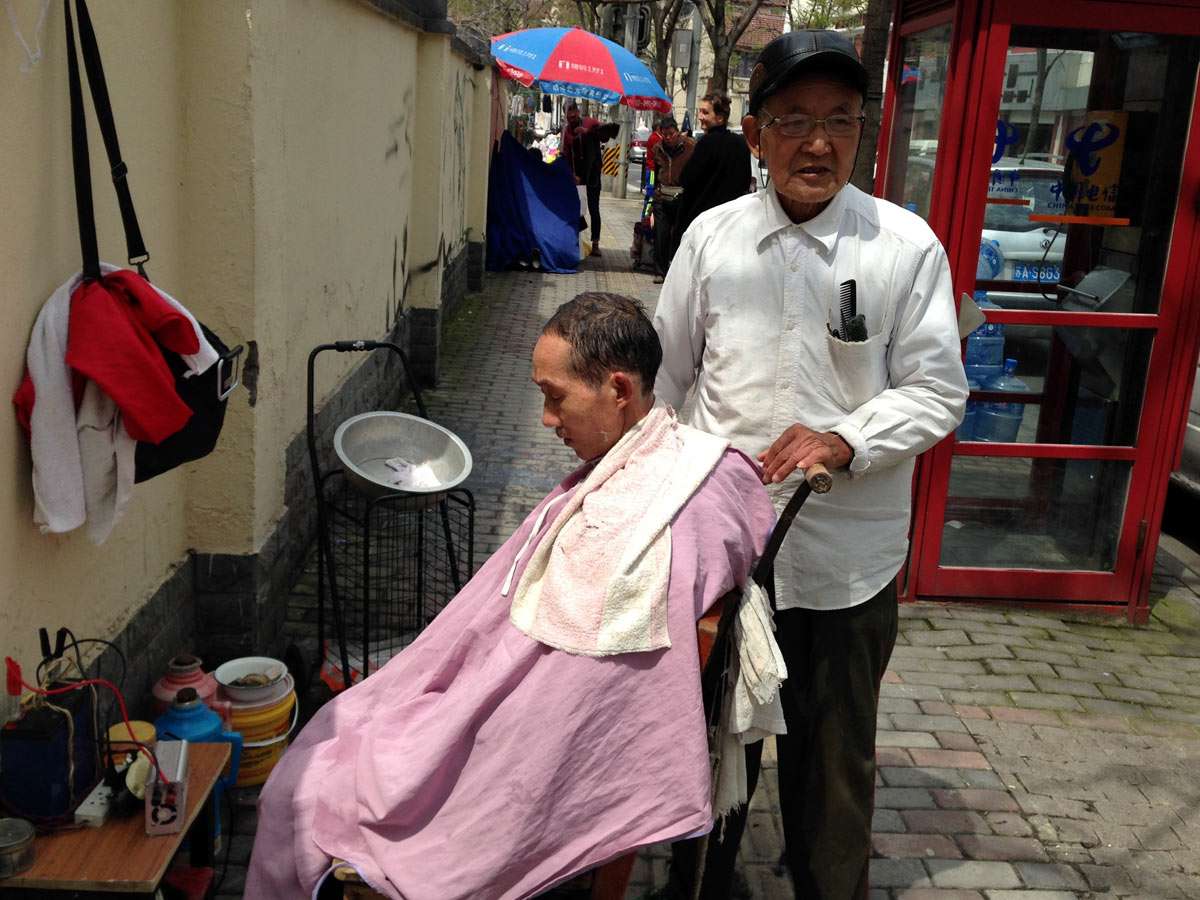streetlife-shanghai-friseur Straßenfriseur schneidet einem Kunden in Shanghai die Haare